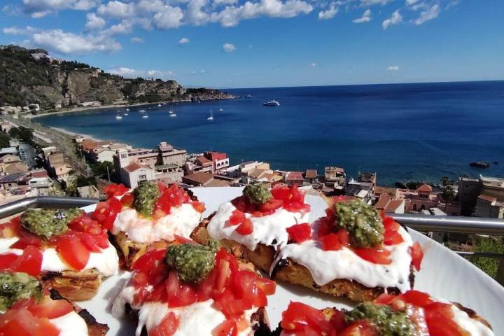 Bruschetta with tomatoes and pesto on a plate overlooking a coastal town and sea.