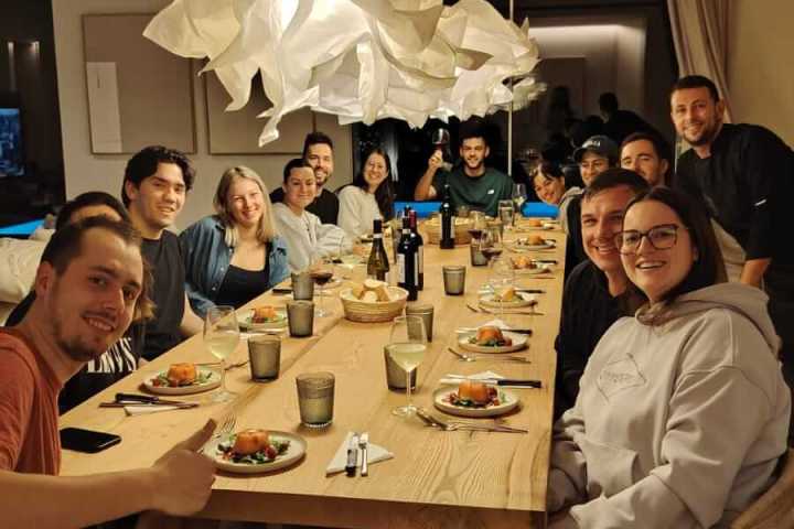 Group of people smiling around a dinner table with plates and drinks.