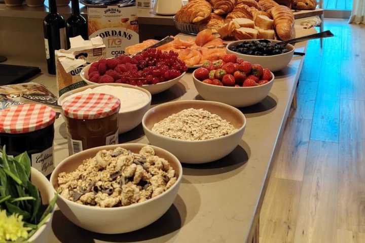 Breakfast buffet with pastries, fruits, cereals, and a Christmas tree in the background.