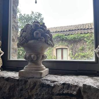 Statues on stone ledge by a window with a view of ivy-covered wall.