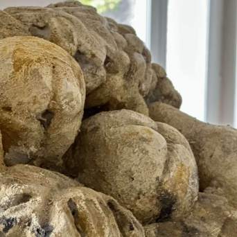 Close-up of beige stone sculpture with carved, rounded shapes near a window.