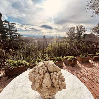 Stone fruit sculpture on a table with a scenic terrace view of trees and sky.