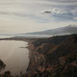 Coastal town with mountains and cloudy sky in the background.