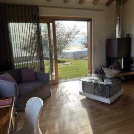 Cozy living room with glass doors, wooden beams, and outdoor view.