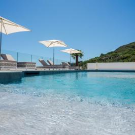 Poolside view with loungers, umbrellas, and clear sky on a sunny day.