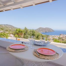 Scenic patio with table set for two overlooking hills and sea view.