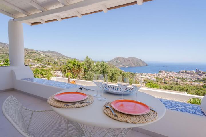 Scenic patio with table set for two overlooking hills and sea view.