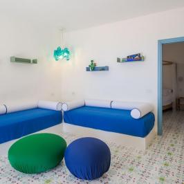 Room with blue sofas, poufs, and vibrant patterned floor tiles.