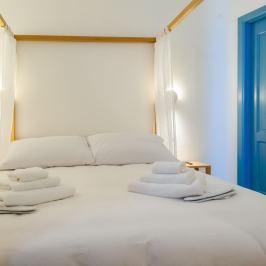 Cozy bed with white sheets and towels, surrounded by sheer curtains.