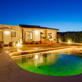 Cozy villa with illuminated pool and patio at twilight.