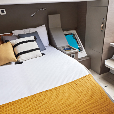 Cozy bedroom with bed, pillows, and porthole window.