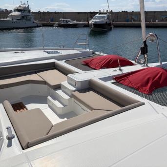 Luxurious yacht deck with cushioned seating, two red covers, and a view of the marina.