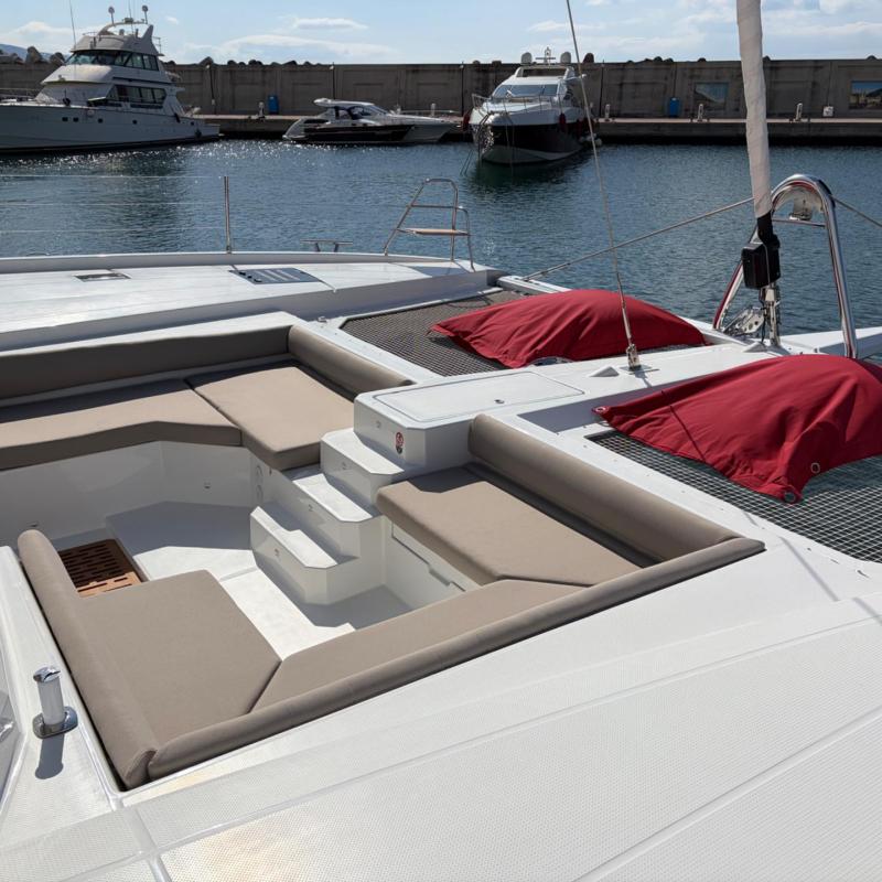 Luxurious yacht deck with cushioned seating, two red covers, and a view of the marina.