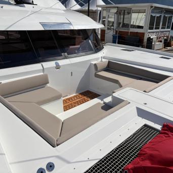 White yacht deck with beige cushioned seating area and windows.