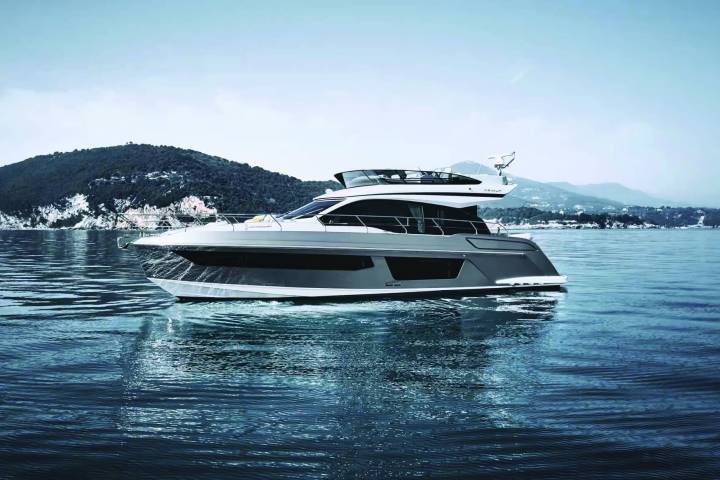 A luxury yacht sailing on calm waters with hills in the background.