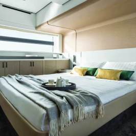 Modern yacht bedroom with a neatly made bed, window view, and decor accents.