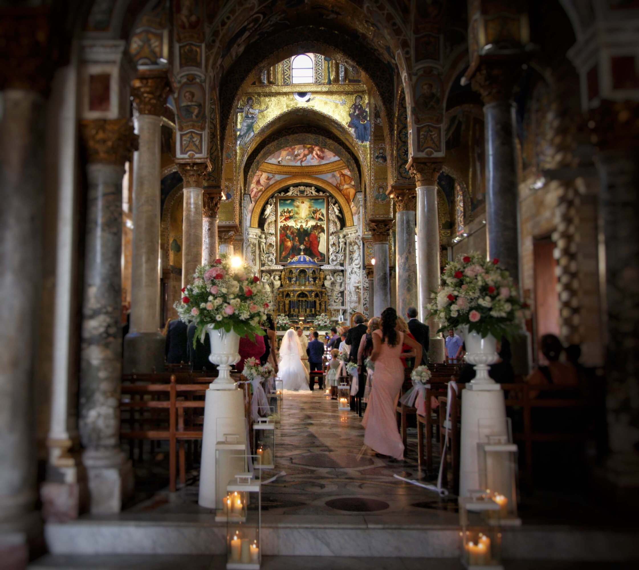 Ornate church interior with wedding ceremony, floral arrangements, and guests seated.